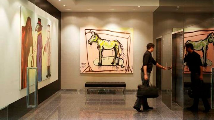 A man inside an art gallery with a large painting of a horse